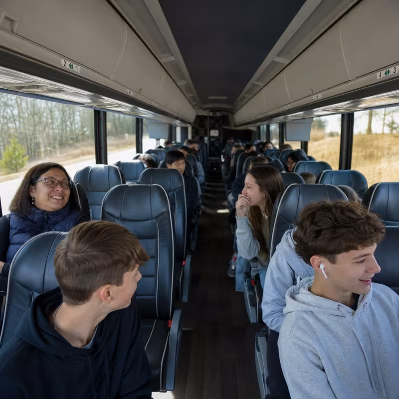 Group boarding a white charter bus for School Transportation transportation in St. Petersburg